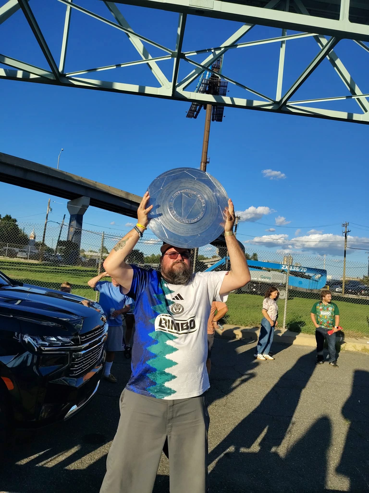 Simo Dollaz holding a large metal plaque outdoors